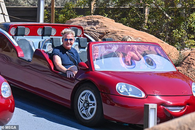 Gordon sat in the front of a red car next to Oscar, who was hugging a stuffed version of Monsters Inc.'s Boo.