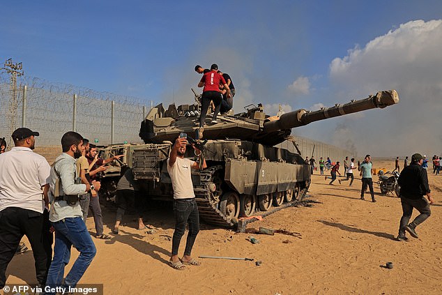 Palestinians take control of an Israeli Merkava battle tank after crossing the border fence with Israel from Khan Yunis in the southern Gaza Strip on October 7, 2023