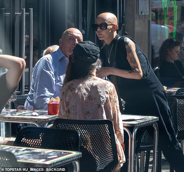 At the café she was joined by a man, whom she leaned over to kiss on the cheek, and a woman who was sitting across from them.