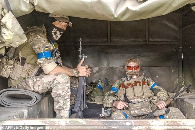 Armed Ukrainian soldiers sit in the back of a truck heading towards the conflict in the Sumy region, near the border with Russia.