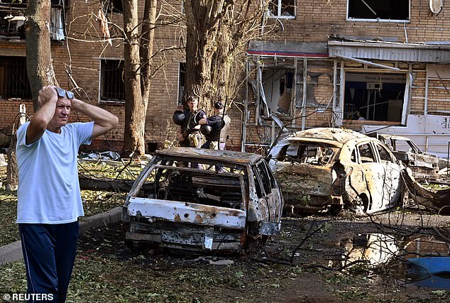 A man reacts to the destruction in the courtyard of a residential building, which local authorities say was hit by debris from a Ukrainian missile destroyed in its Kursk offensive.