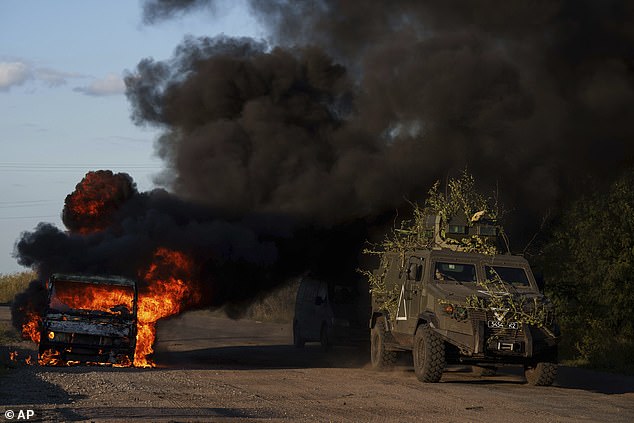 A Ukrainian armored military vehicle drives past a burned-out car near the border on Wednesday.