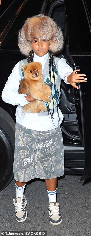 North, who is already a true fashionista, paired her eye-catching headpiece with a blue button-down shirt, a grey and blue argyle vest and baggy camouflage shorts.