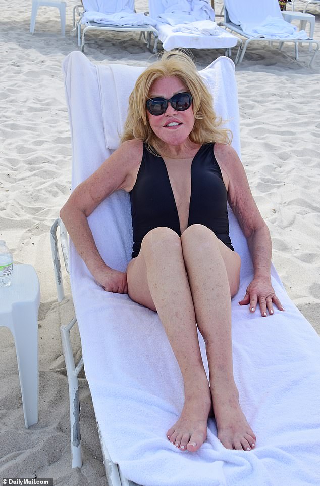 Wildenstein, who earned the nickname 'Catwoman' after spending millions on plastic surgery to look feline, wore a deep-cut black one-piece swimsuit and accessorised with oversized dark sunglasses.