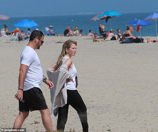 David stayed close to his wife as they walked towards the ocean and took a long walk with their friends following them.