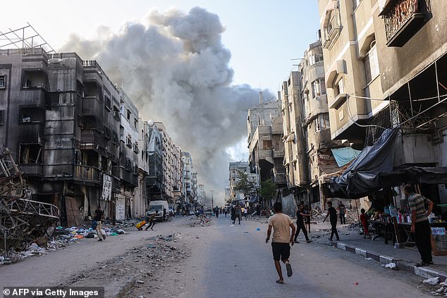 Palestinians run towards a column of smoke rising after Israeli shelling hit a school compound on August 3.