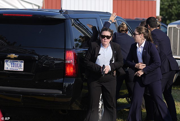 Secret Service agents stand guard outside former President Trump's motorcade shortly after he was shot by Thomas Matthew Crooks at his Butler campaign stop