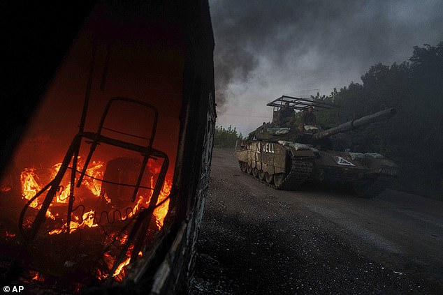 A Ukrainian tank drives past a burning car near the Russian-Ukrainian border, in the Sumy region, Ukraine, Wednesday, Aug. 14, 2024.