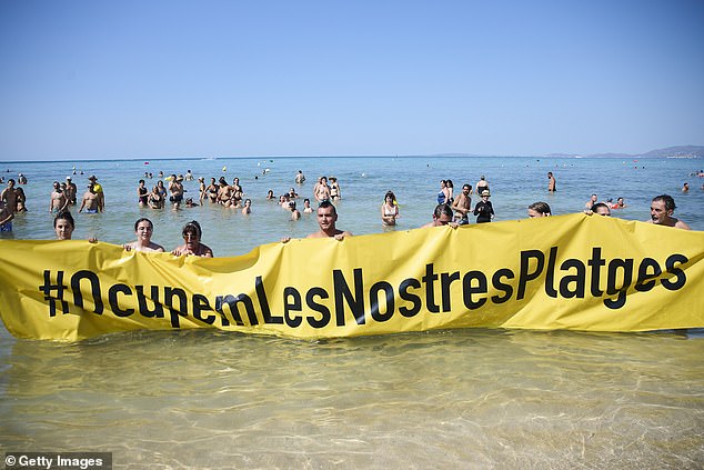 Members of the Mallorca Platja Tour association demonstrate against tourism with a banner reading 'Let's occupy our beaches!' on the beach of Palma de Mallorca yesterday