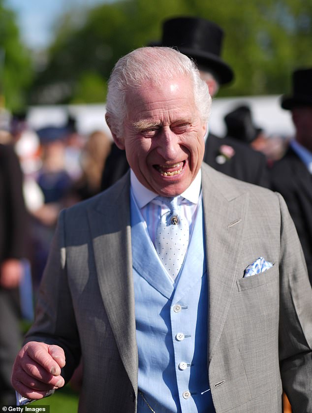 King Charles III speaks to guests attending a royal garden party at Buckingham Palace on the same day Harry was in the UK.