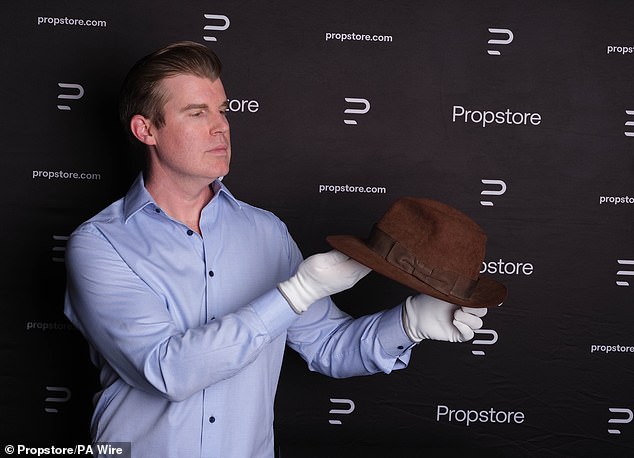 On top of the props: An auctioneer holds the famous fedora hat at the sale in Los Angeles