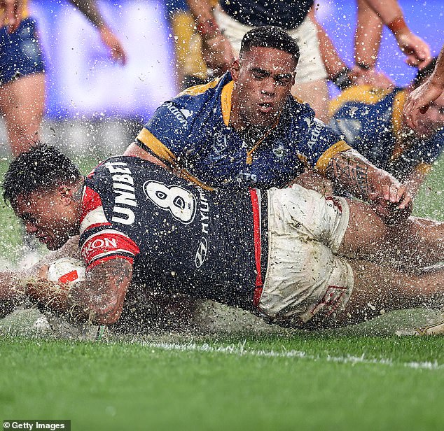 Roosters' Spencer Leniu scores a try by sliding through a huge pool of water at Allianz Stadium on Friday