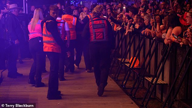 The camera then panned out into the crowd to show several security officers dragging a blonde-haired person over barriers before escorting her out of the festival.