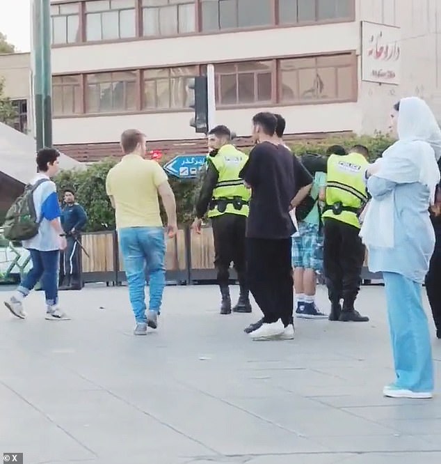 In one video, a teenager wearing Bermuda shorts and a backpack is seen with his hands cuffed behind his back as officers slowly lead him away.