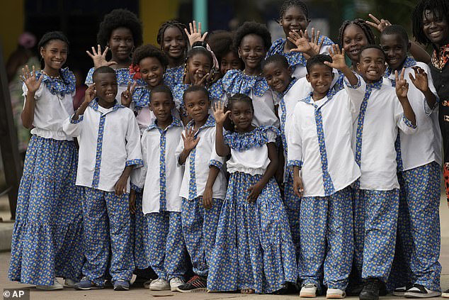 Members of a children's choir wave as they await the arrival of Prince Harry and Meghan