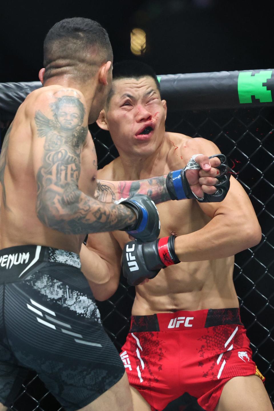 China's Li Jingliang (in red) is knocked out by Brazil's Carlos Prates at their Ultimate Fighting Championship (UFC) 305 men's welterweight event at the Perth Arena in Perth on August 18, 2024. (Photo by COLIN MURTY / AFP) / -- IMAGE RESTRICTED TO EDITORIAL USE - STRICTLY NO COMMERCIAL USE -- (Photo by COLIN MURTY/AFP via Getty Images)