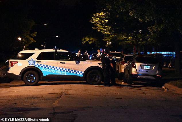 Police officers stand on a residential street in Chicago's Bronzeville neighborhood Saturday night where a 28-year-old man was shot and killed.