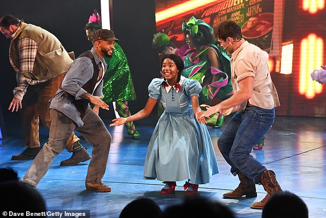 In the photos, the singer, dressed in a brown baker boy shirt, a grey button-down shirt and a brown vest, was all smiles as he sang and danced alongside the production's Dorothy.