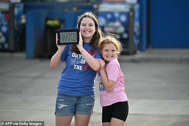 Two girls hold a tablet that says 