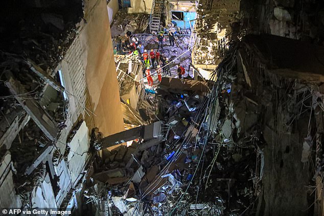 A picture taken on July 30, 2024 shows rescuers on the street near a building with its upper floors destroyed following an Israeli military strike in the southern suburb of Beirut.