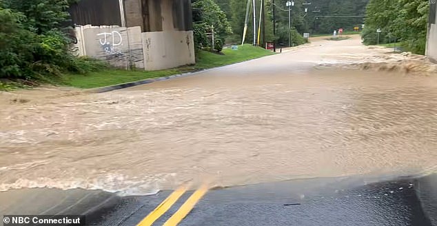 Pictured: Floodwater overflows across a road in Monroe, Connecticut, on Monday