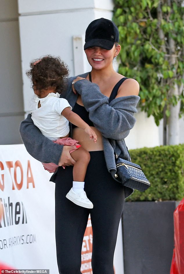 Chrissy was dressed to be comfortable and practical in a black sports bra and matching leggings with a grey zip-front hoodie.