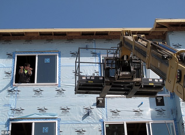 The median sales price of a home in the Flickertail State last year was $201,991, compared with $168,105 in 2011. (Pictured: Construction workers lifting materials for a new apartment complex in Bismarck in 2012)