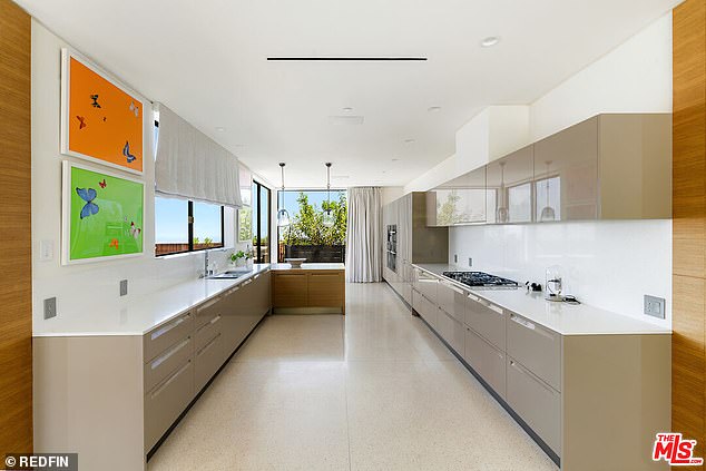 The kitchen of the Beverly Hills home also features double ovens and glossy-finished floating cabinets with custom track lighting and terrazzo floors.