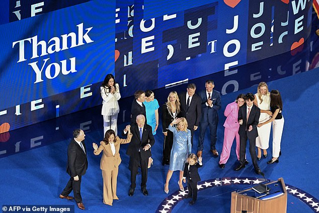 President Joe Biden raises hands with Vice President Kamala Harris as family members flooded the stage after he concluded his remarks at the Democratic National Convention on Monday night.