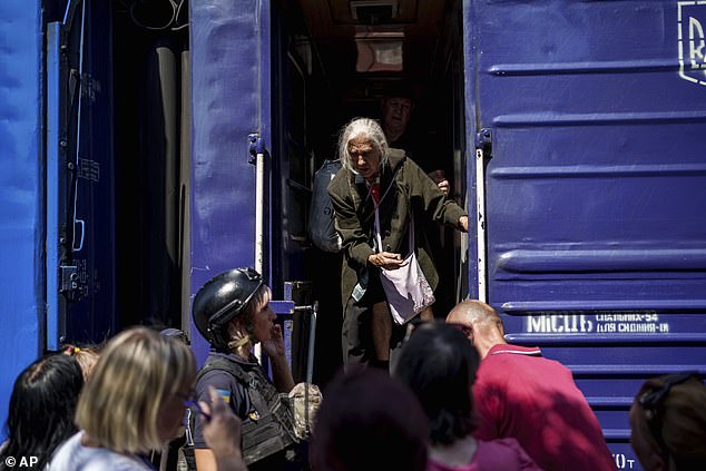 To escape the advancing Russian forces, Ukrainians boarded trains and buses (Pictured: A woman boards the evacuation train in Pokrovsk, Donetsk region)