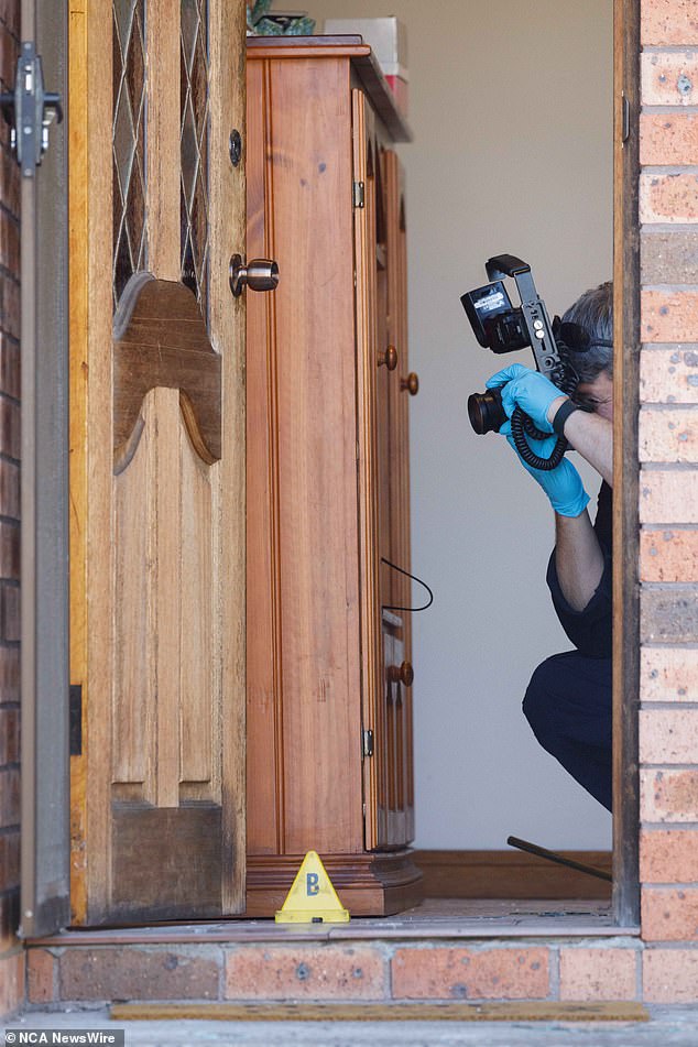 Forensic officers are seen inspecting the front door of the house.