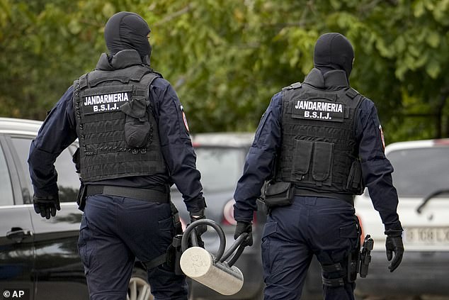 Police officers wearing balaclavas hold a battering ram used to break down a door outside the residence of internet influencer Andrew Tate