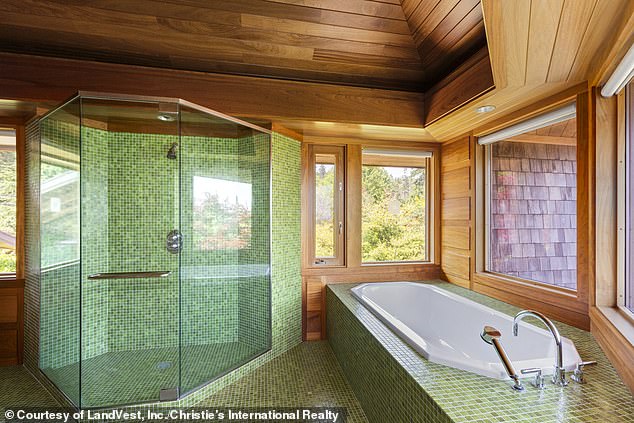 A large bathroom (pictured) is accented with wood and sage green tiles on the floor and glass shower.