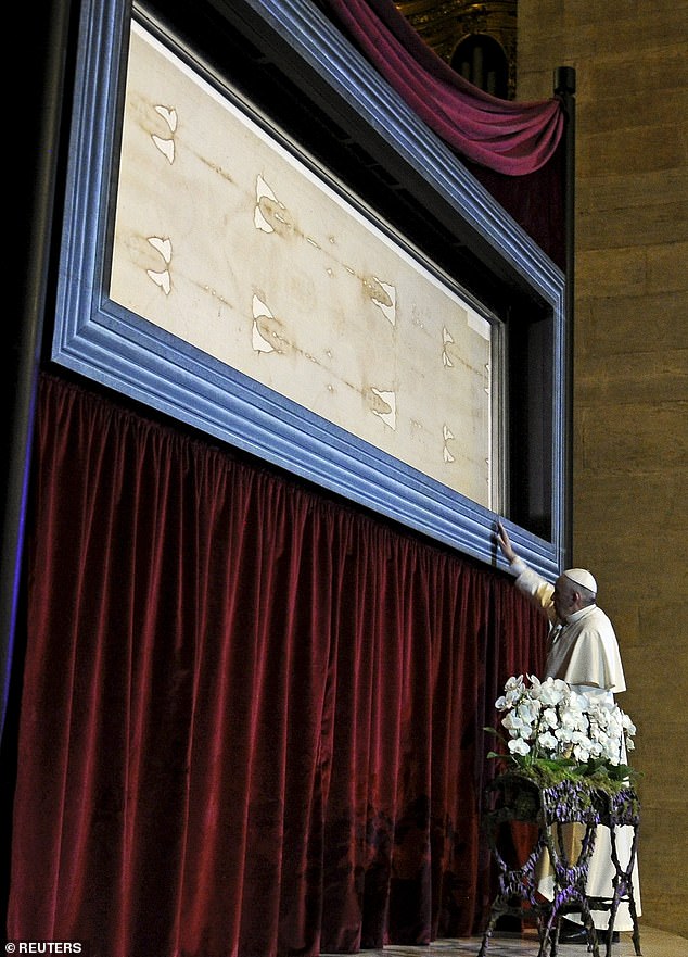 The Shroud first appeared in 1354 in France. After initially denouncing it as a fake, the Catholic Church has accepted it as authentic. Pictured, Pope Francis touches the Shroud of Turin during a visit in 2015