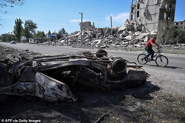 A man rides a bicycle through the rubble of a multi-storey building, destroyed a few days earlier following an attack in the town of Myrnohrad, on August 21, 2024.