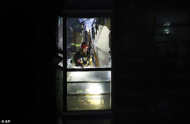 A firefighter is seen behind a broken window searching for missing people in the hotel.