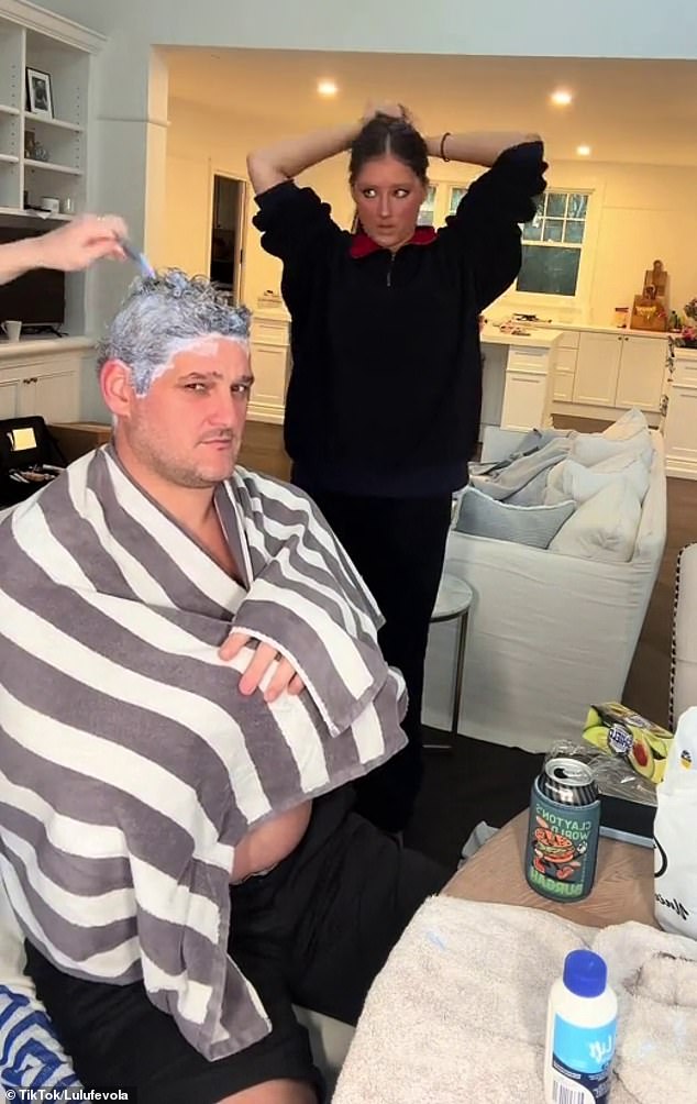 An unsuspecting Brendan sat topless at his dining table with a towel wrapped around his shoulders and his hair covered in bleach. He is pictured with his daughter Lulu.