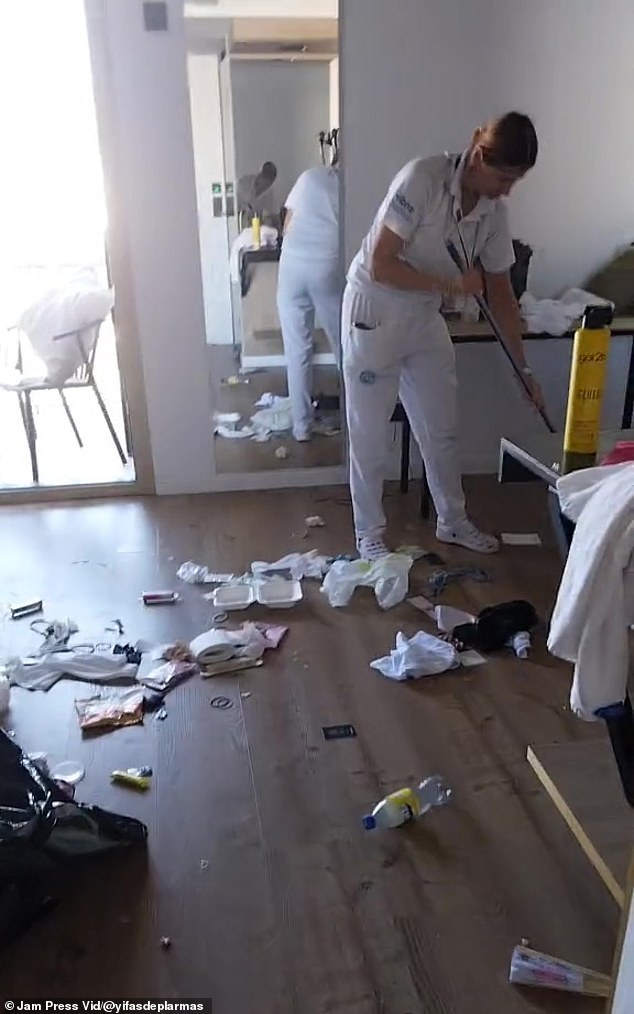 Toilet paper rolls and empty plastic bottles can be seen scattered around the suite as a maid cleans.