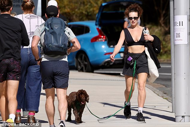 She looked relaxed but in a hurry as she walked down the street with her puppy on a leash.