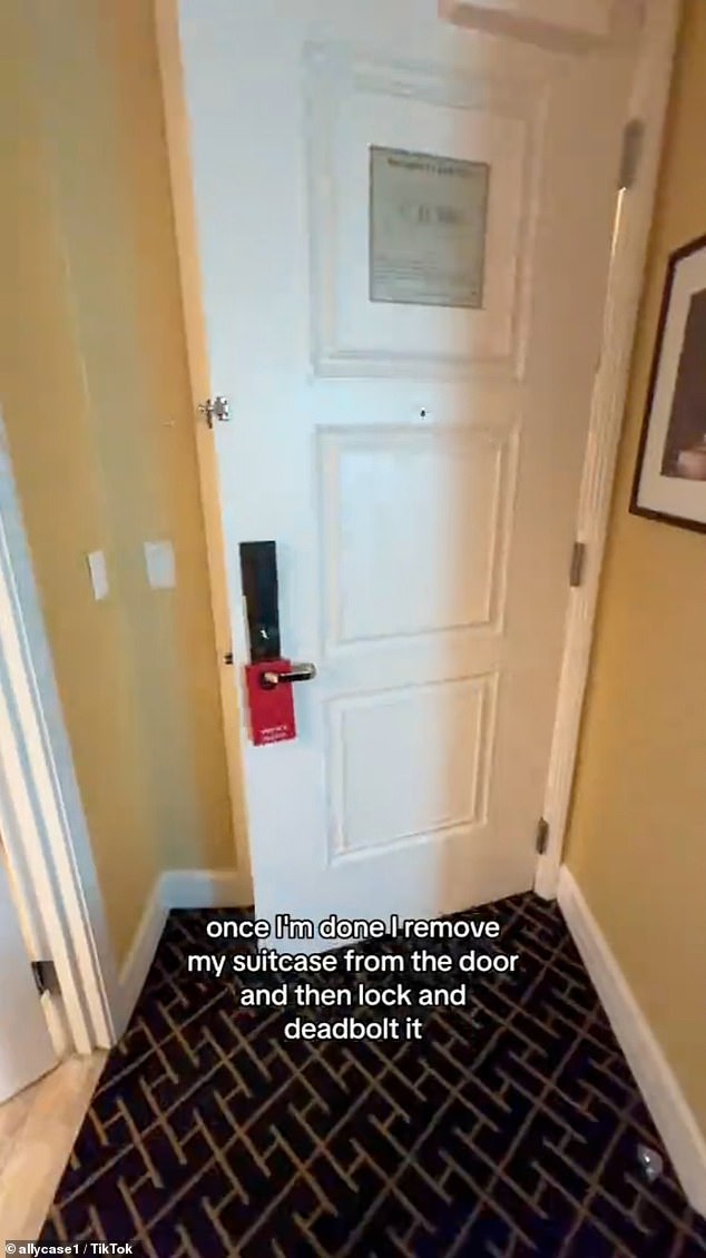 After completing his checks, he removes the suitcase from the door, then locks and latches it.