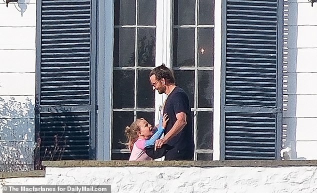 In exclusive photos obtained by DailyMail.com, Bradley is seen enjoying the summer sunshine with his seven-year-old daughter as they stood on a balcony and at one point, flashed a big smile during a light-hearted moment.