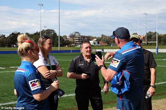 Officials from both teams and an NRL representative (in black jersey, centre) are pictured discussing the delay caused by the lack of medical staff.