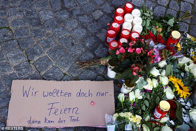 A sign that says: "We just wanted to celebrate, but then death came." It is placed next to flowers and candles.