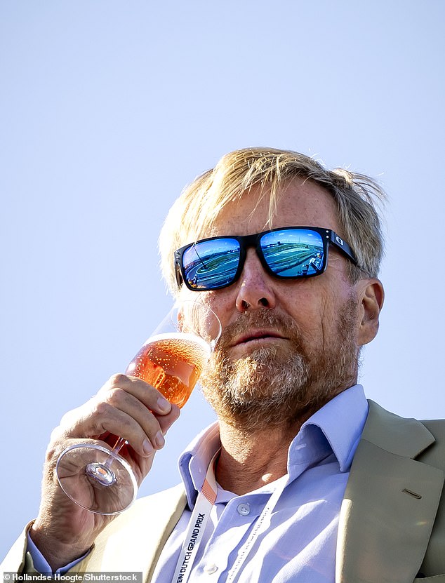 In one snap, the King can be seen enjoying a glass of champagne as he watched the drivers race around the track.