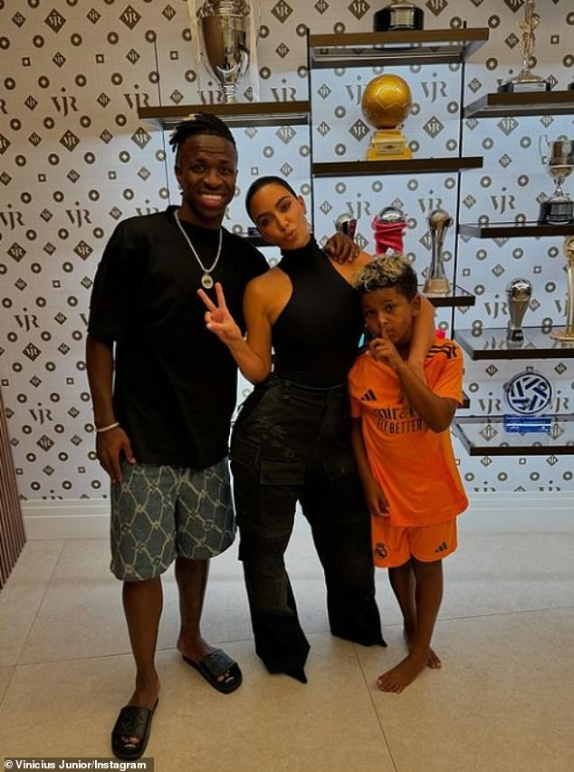 The influencer looked incredible in a black bodysuit and cargo jeans as she posed with Saint and Vinicius Jr for an Instagram photo.