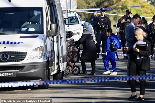 Witnesses reported hearing at least eight shots and that the victim was allegedly attacked in the garage of an apartment building (pictured: police at the scene)