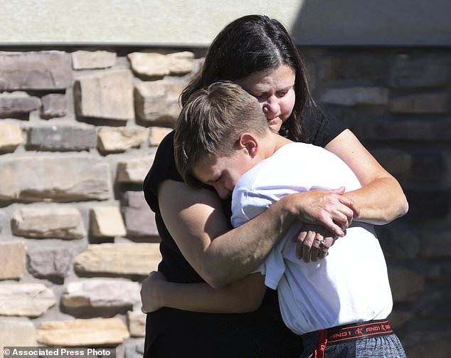 Neighbors hug each other after a 5-year-old boy accidentally shoots himself with a gun he found in his parents' bedroom in Santaquin, Utah