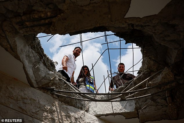 People look at damage to a residential building following a direct hit by a projectile, after Hezbollah launched hundreds of rockets and drones towards Israel in what the Iran-backed movement said was a response to the killing of a senior commander in Beirut last month, northern Israel August 25, 2024