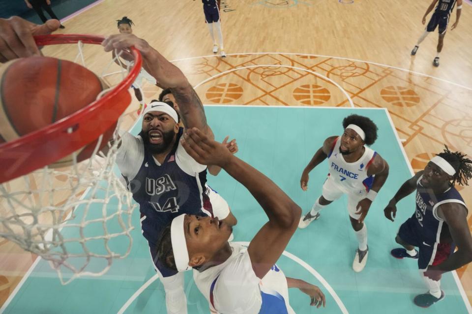 American Anthony Davis dunks over Frenchman Bilal Coulibaly during the gold medal match at the Paris Olympics.