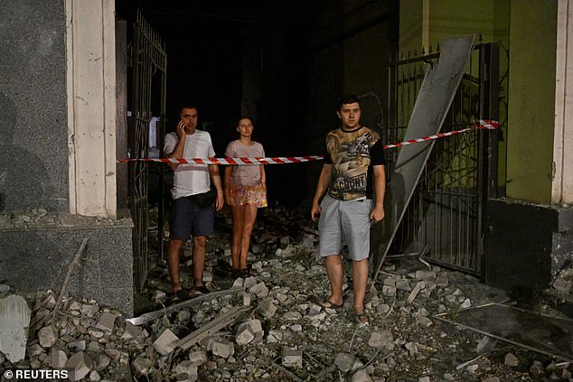 Local residents stand at the site of a Russian missile strike, amid Russia's attack on Ukraine, in Kryvyi Rih.